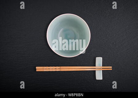 Empty bowl and  bamboo chopsticks on black slate background, top view Stock Photo