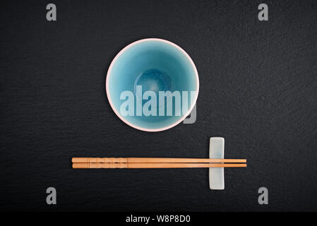Empty bowl and  bamboo chopsticks on black slate background, top view Stock Photo