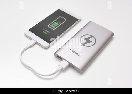 USB charger plugged in to smart phone. Power bank, mobile phone battery on desk concept Stock Photo