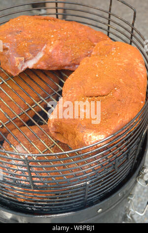 Italy, Lombardy, Crema, Food Street Festival, Pork Shoulders Slowly Cooking Over a Smokey Barbecue Fire Stock Photo