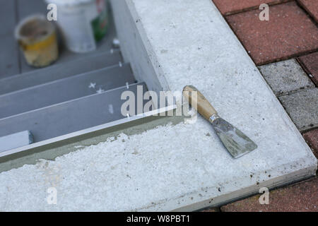 Tiler hands working on a new house entrance, local and professional handyman applying tiles to the steps. Stock Photo