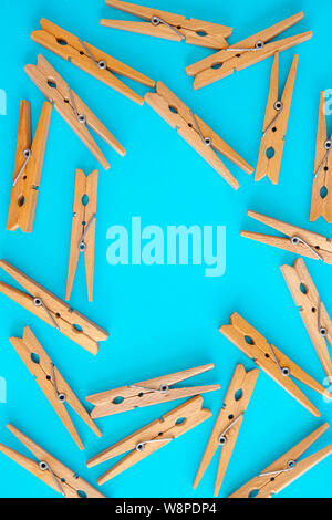 Wooden yellow clothespins are scattered on a cyan-blue background. Frame of clothespins. View from above. Copy space. Flat lay. The concept is natural Stock Photo