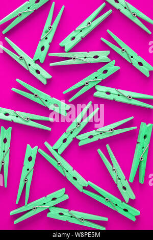 Wooden pink-crimson clothespins are scattered on a cyan-green background. Frame of clothespins. View from above. Copy space. Flat lay. The concept is Stock Photo