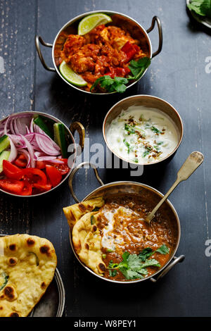 Indian curry meal with black lentils dal, spicy potatoes, rice, naan bread and raita Stock Photo