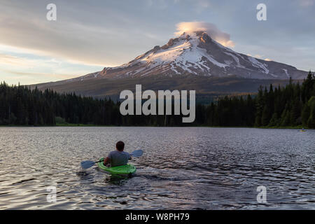 Trillium Lake, Mt. Hood National Forest, Oregon, United States of America - June 30, 2019: Adventurous man kayaking in a beautiful lake with Hood Moun Stock Photo