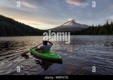 Trillium Lake, Mt. Hood National Forest, Oregon, United States of America - June 30, 2019: Adventurous man kayaking in a beautiful lake with Hood Moun Stock Photo