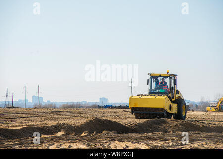 heavy duty machinery working on highway construction site. Bulldozer, dumper truck, soil compactor and vibratory roller Stock Photo