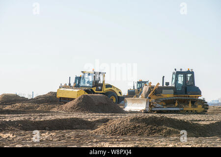 heavy duty machinery working on highway construction site. Bulldozer, dumper truck, soil compactor and vibratory roller Stock Photo