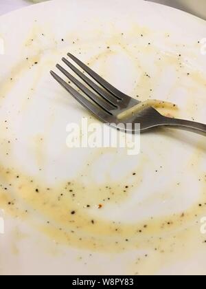 Empty pasta plate on wooden table after eating all Stock Photo
