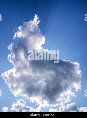 Sun behind clouds against a blue sky. Clouds that block the sun can have a "silver lining". Stock Photo