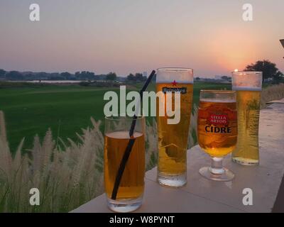 Different brand of beer arranged on a row facing a golf course at sunset Stock Photo