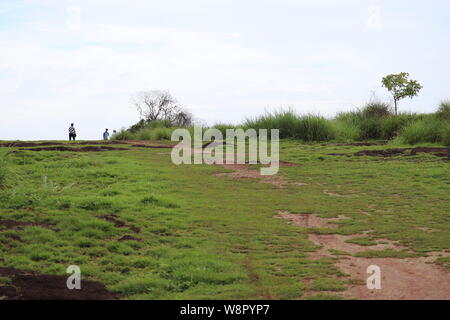 Green lawn at the top of a hill in the background of blue sky with clouds Stock Photo