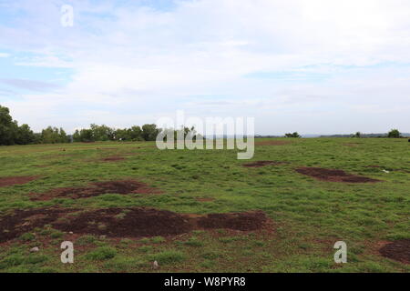 Green lawn at the top of a hill in the background of blue sky with clouds Stock Photo