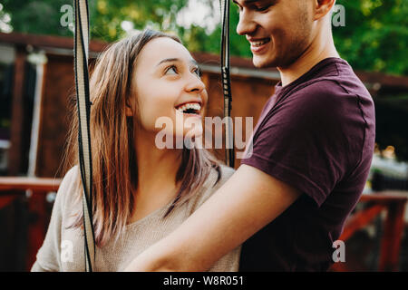 Loving young man and woman in green park preparing for extreme entertaining ride and looking at each other with love Stock Photo