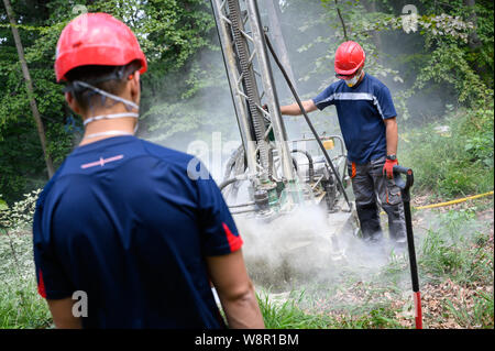 Wittmar, Germany. 08th Aug, 2019. Two men operate a drill that drills a 15-meter-deep hole to place an explosive charge that is used to measure the soil structure around the Asse 2 final nuclear repository. Around 6500 explosive charges are to be distributed in the forest. 45,000 seismographic sensors will then be distributed on the site to record the vibrations of the explosions. Credit: Christophe Gateau/dpa/Alamy Live News Stock Photo