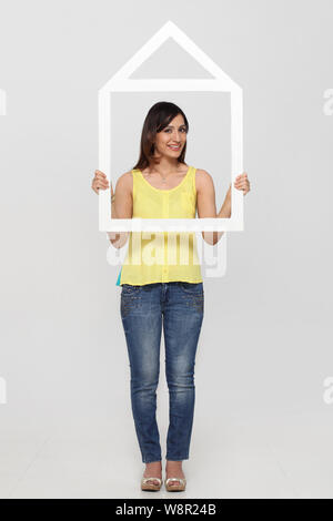 Young woman holding a dream home shape frame Stock Photo