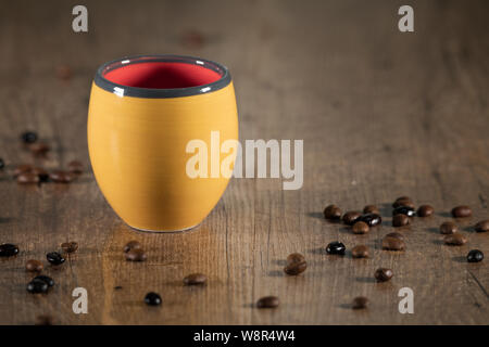 Detail of roasted coffee seeds on the table around a yellow coffee cup - Close-up Stock Photo
