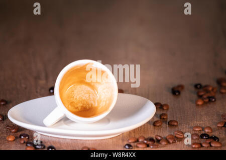 A White Cup of Coffee Surrounded by Roasted Coffee Seeds - Close-Up Stock Photo