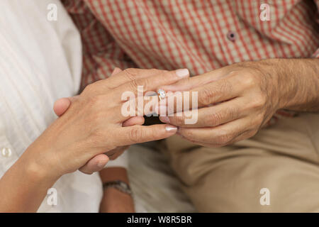 Old man placing ring on his wife finger Stock Photo