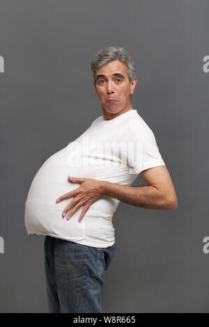 Senior man pretending to be a pregnant woman Stock Photo