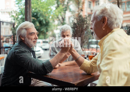 Men trying arm-wrestling while sitting outside pub Stock Photo
