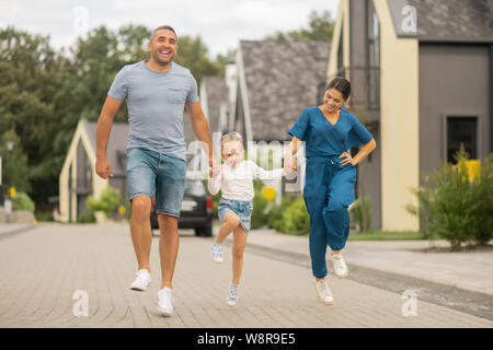 Daughter running while having fun with parents Stock Photo