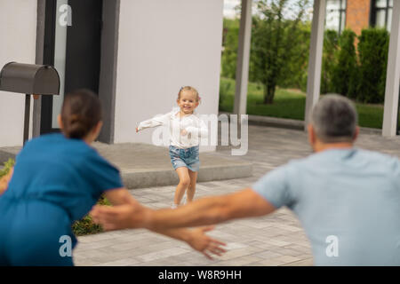 Cheerful daughter meeting parents coming back from work Stock Photo