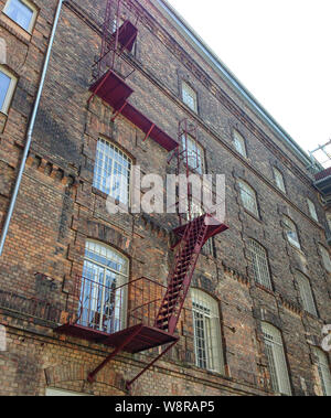brick wall with red iron staircase and ladder Stock Photo