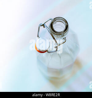 Top view of a glass bottle with a  wire bail clasp ceramic stopper on a blue, pink and orange stripped tablecloth Stock Photo