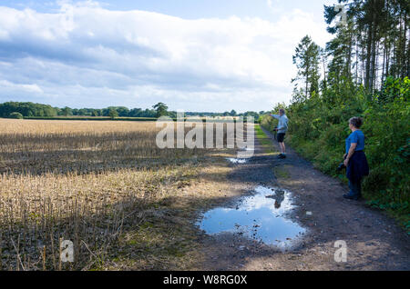 A couple ramble down a dirt track past fields through the Staffordshre countryside near the village of Perton near Wolverhampton in the UK Stock Photo