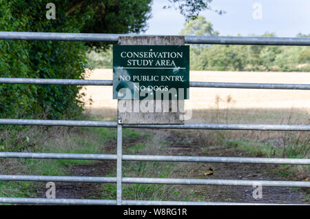 A sign on a metal gate informers members of the public that they are not allowed entry past the gate which is a conservation study area. Stock Photo