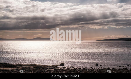 Evening sunshine filtering through clouds over Gair Loch and distant islands in the Highlands of Scotland Stock Photo