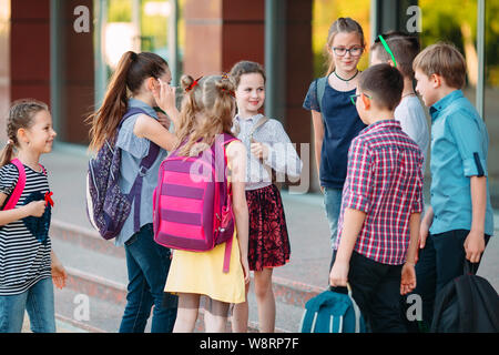 Schoolmates go to school. Students greet each other. Stock Photo