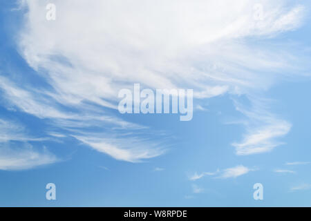 White fluffy cirrus clouds in a stratosphere. Translucent fiber like spindrift clouds high in the blue summer sky. Stock Photo