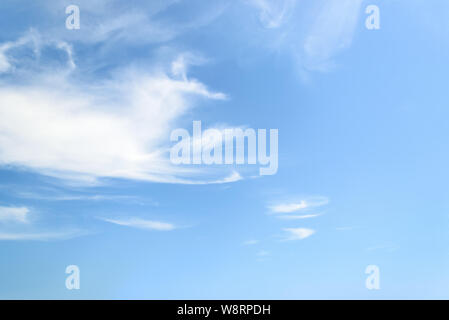 White fluffy cirrus clouds in a stratosphere. Light translucent fiber like spindrift clouds high in the blue summer sky. Stock Photo