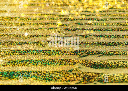 Photo of holographic real texture in gold yellow colors, colorful iridescent surface. Holographic color wrinkled foil. Colored glitter. Shining background. Stock Photo