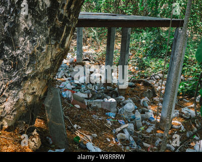 Garbage under the tree.Spilled garbage city. Empty used dirty plastic bottles. Dirty. Environmental pollution. Ecological problem. Stock Photo