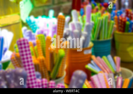 Blurred multi-color background storefront dishes, cutlery spoons, forks, knives with colored handles in multi-colored buckets, background, blur, defoc Stock Photo