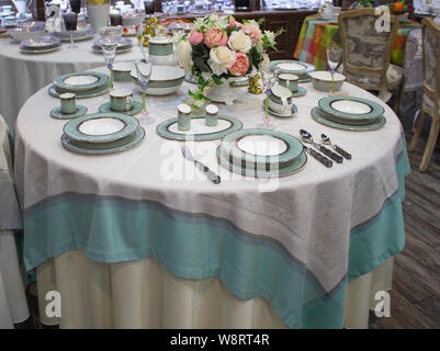 Table setting for 6 persons. Turquoise blue service set on a round table with a tablecloth in color. Festive table, dining table decor Stock Photo