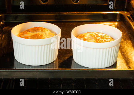 Egg omelette baked in the oven in white tins, two servings of omelette for breakfast, cooking in the oven Stock Photo