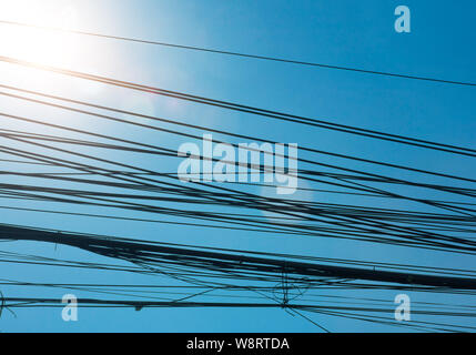 Incredible tangle of electric cables on blue sky in bangkok thailand, Cables silhouette Stock Photo