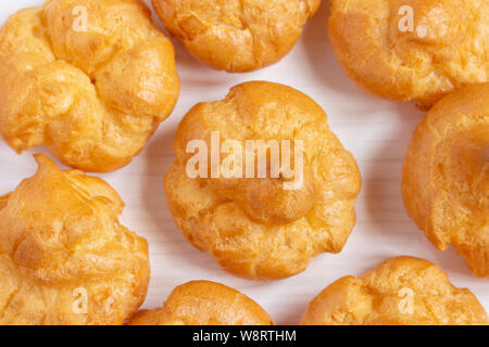 Profiteroles close-up, macro top view. Sweet air cakes profirtoli, homemade pastry dessert treat. Dough Cookies choux pastry biscuits Stock Photo