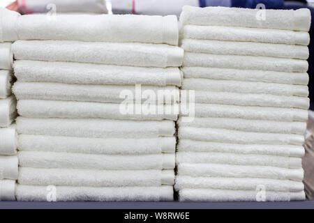 A stack of white terry towels, a pantry at the hotel, a clean towel for visitors and customers Stock Photo