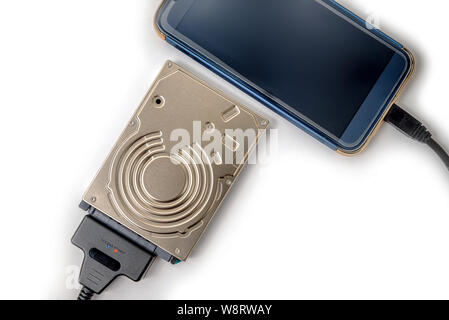 hdd 2.5 hard drive disk connected to smartphone via sata usb cable closeup overhead view Stock Photo