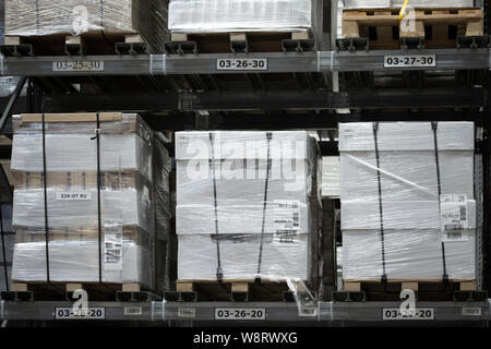 Warehouse with large pallets with boxes, lots of packaged goods in stock. White boxes in pallets on the shelves of a huge warehouse store Stock Photo