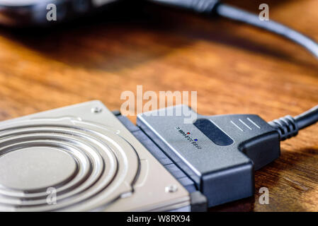 hdd 2.5 internal hard drive disk connected to laptop via sata usb cable on wooden table closeup view Stock Photo