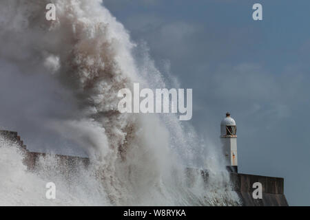 Huge ocean waves crashing into a sea wall and lighthouse (Porthcawl, South Wales, UK) Stock Photo
