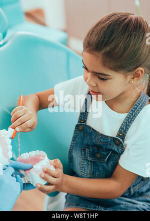 smiling mixed raced girl brushing teeth at dental clinic Stock Photo