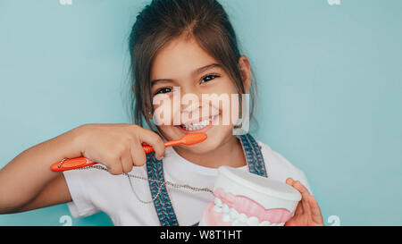 smiling mixed raced girl brushing teeth at blue background. Stock Photo