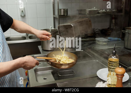 Chef is cooking pasta in professional kitchen Stock Photo